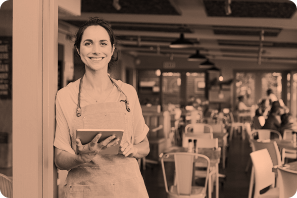 A solopreneur smiles while on her tablet outside of her business